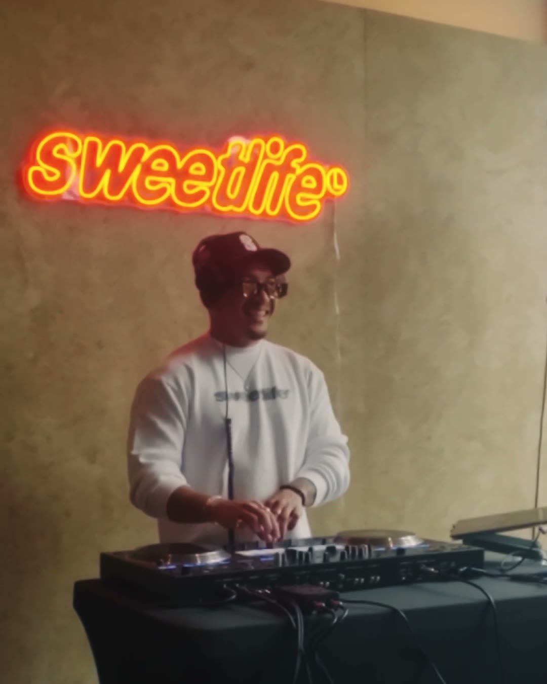 DJ under the SweetLife neon sign at Sweet Life Sessions