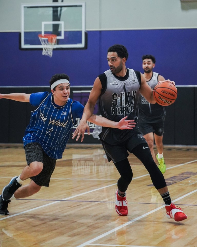 A basketball player dribbles past a defender on an indoor court at the Kings of Seattle tournament.