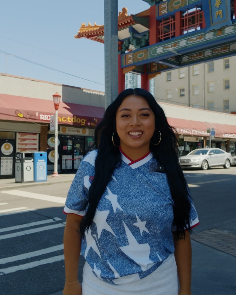Teena Thach smiling in front of the Chinatown Gate in Seattle's Chinatown-International District.
